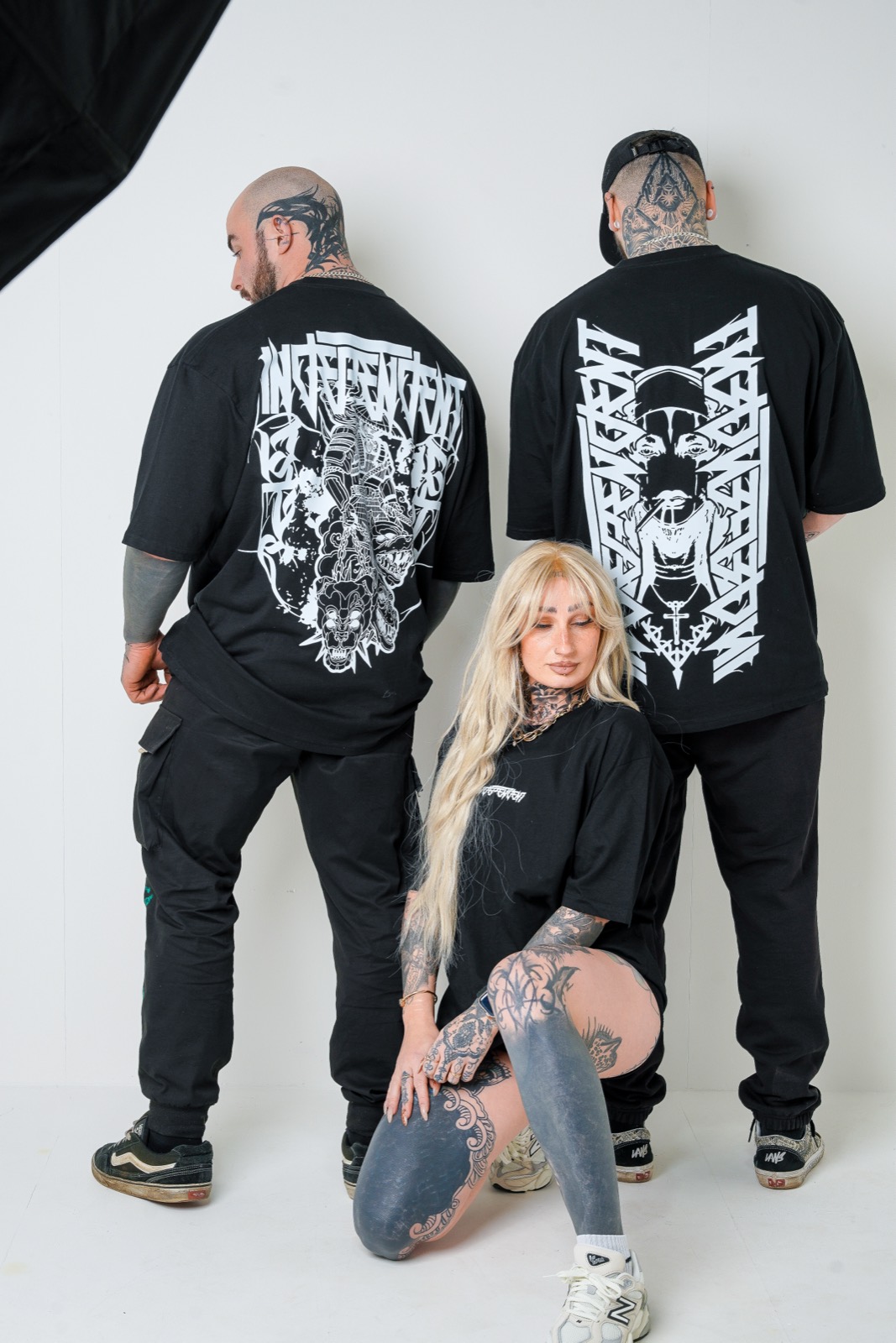 Two oversized tees seen from the back, Samurai and Reaper prints, with a crew member kneeling in front